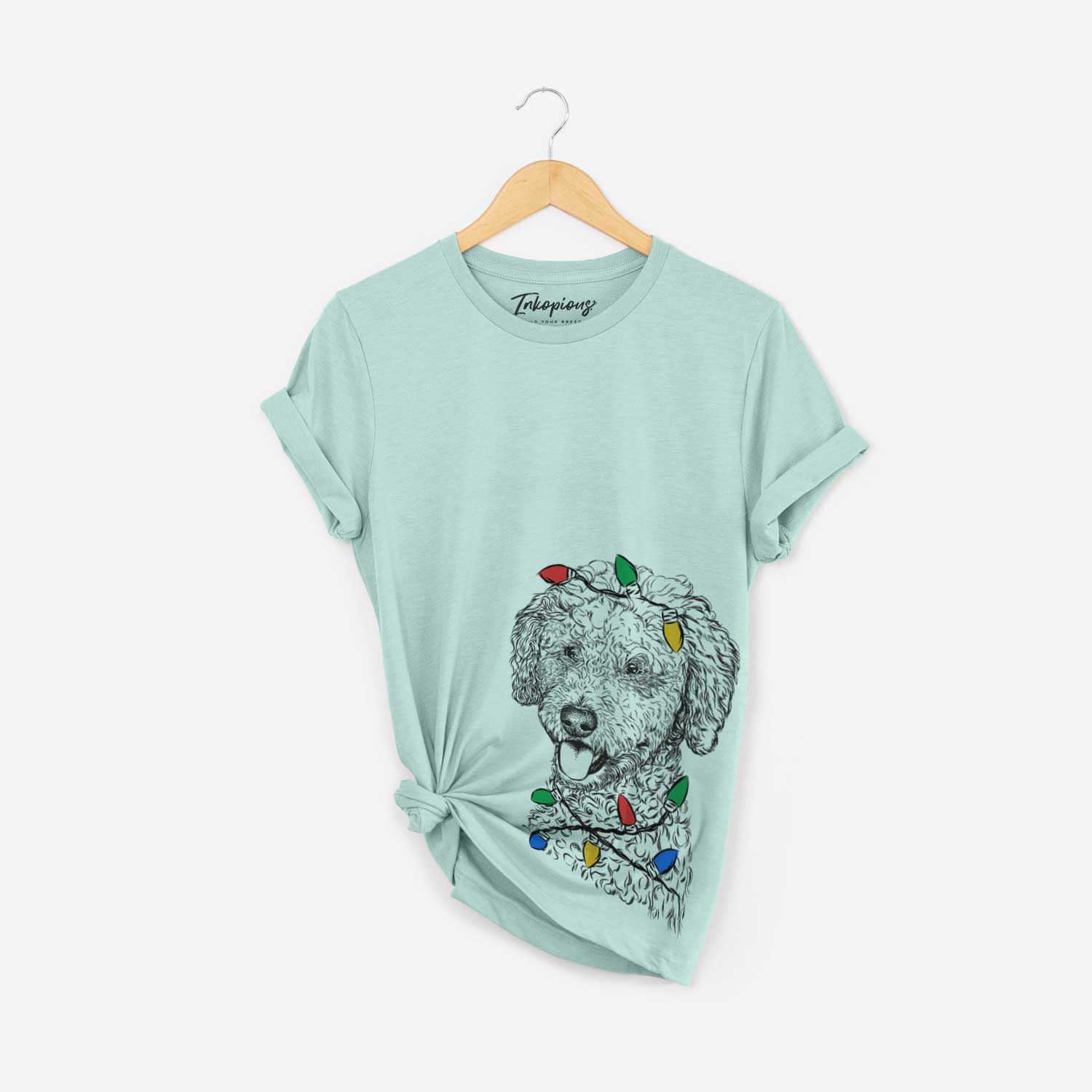 Hand-drawn sketch of Marlow the Goldendoodle wrapped in Christmas lights on a Heather Sage Unisex crewneck