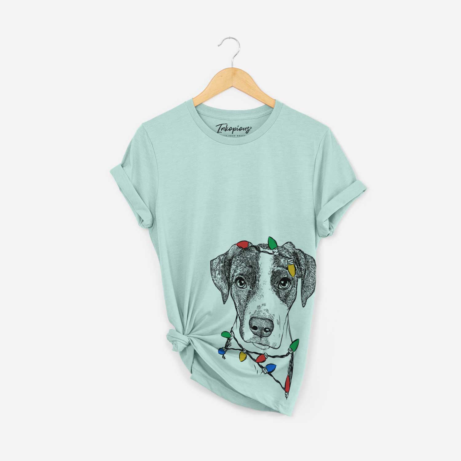 Hand-drawn sketch of Milo the Mixed Breed wrapped in Christmas lights on a Heather Sage Unisex crewneck