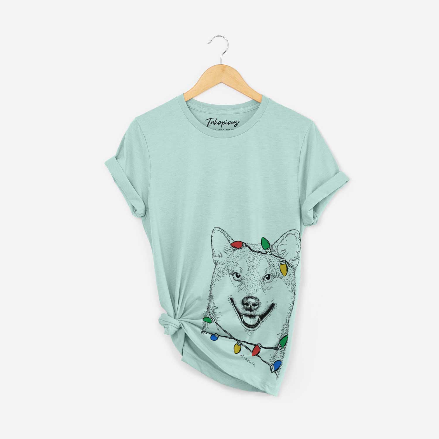 Hand-drawn sketch of Mitsu the Shiba Inu wrapped in Christmas lights on a Heather Sage Unisex crewneck