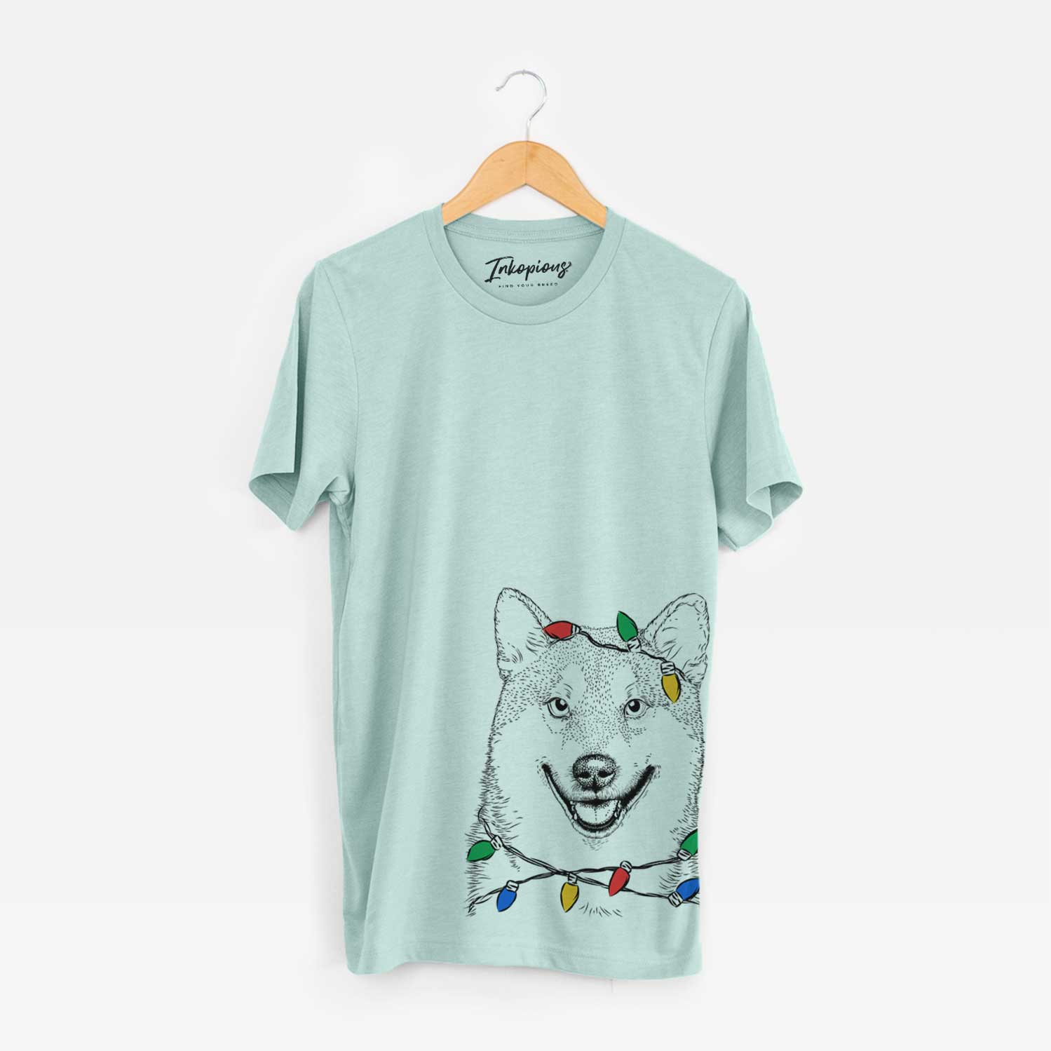 Hand-drawn sketch of Mitsu the Shiba Inu wrapped in Christmas lights on a Heather Sage Unisex crewneck
