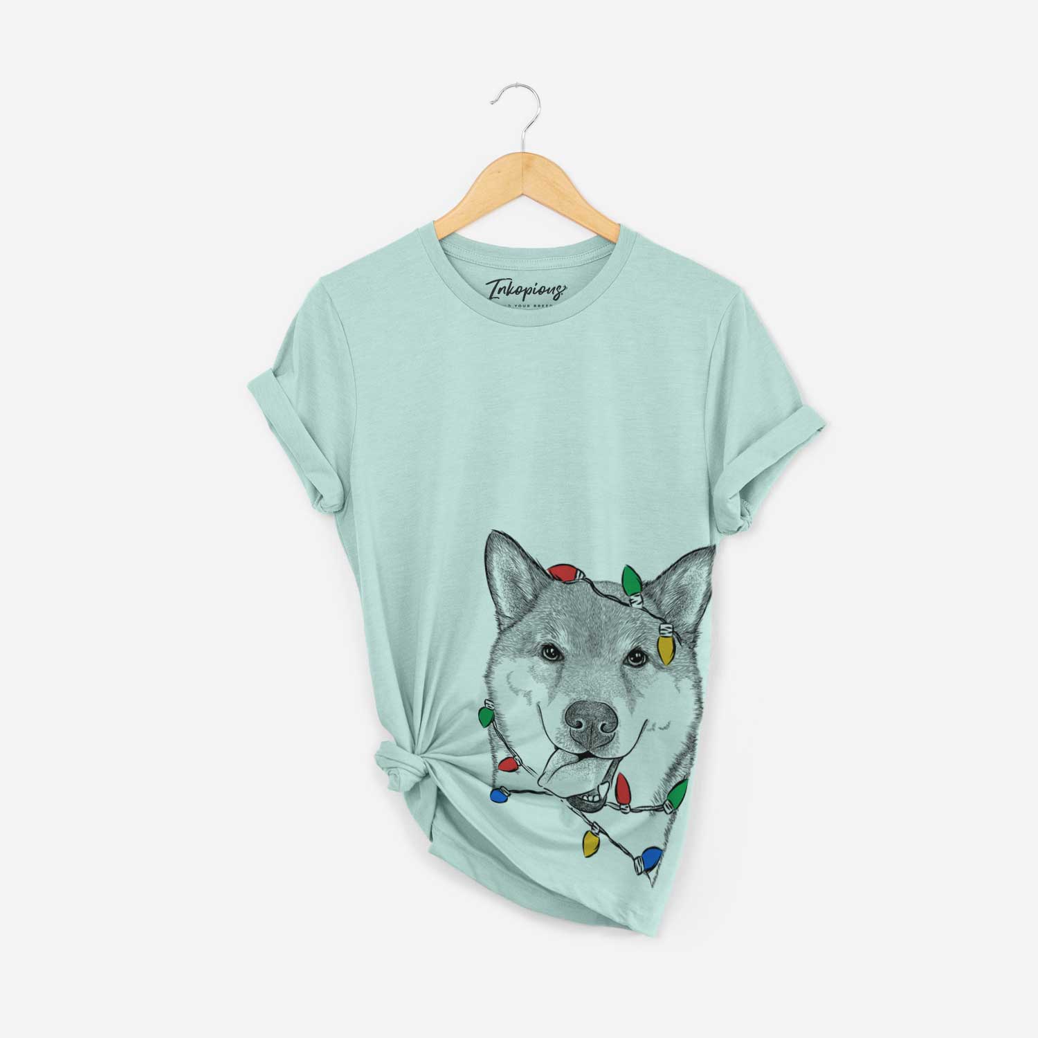 Hand-drawn sketch of Mothra the Shiba Inu wrapped in Christmas lights on a Heather Sage Unisex crewneck