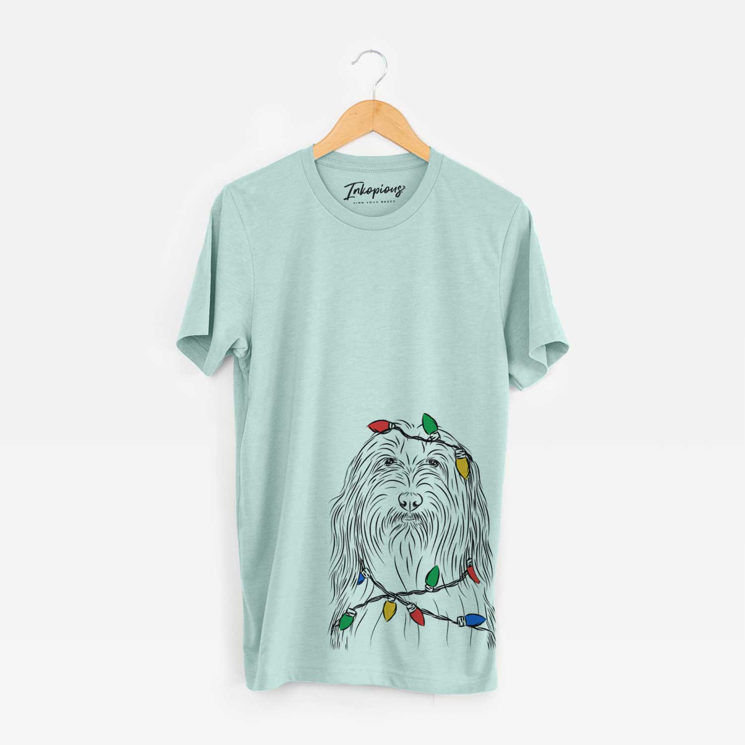 Hand-drawn sketch of Murray the Bearded Collie wrapped in Christmas lights on a Heather Sage Unisex crewneck
