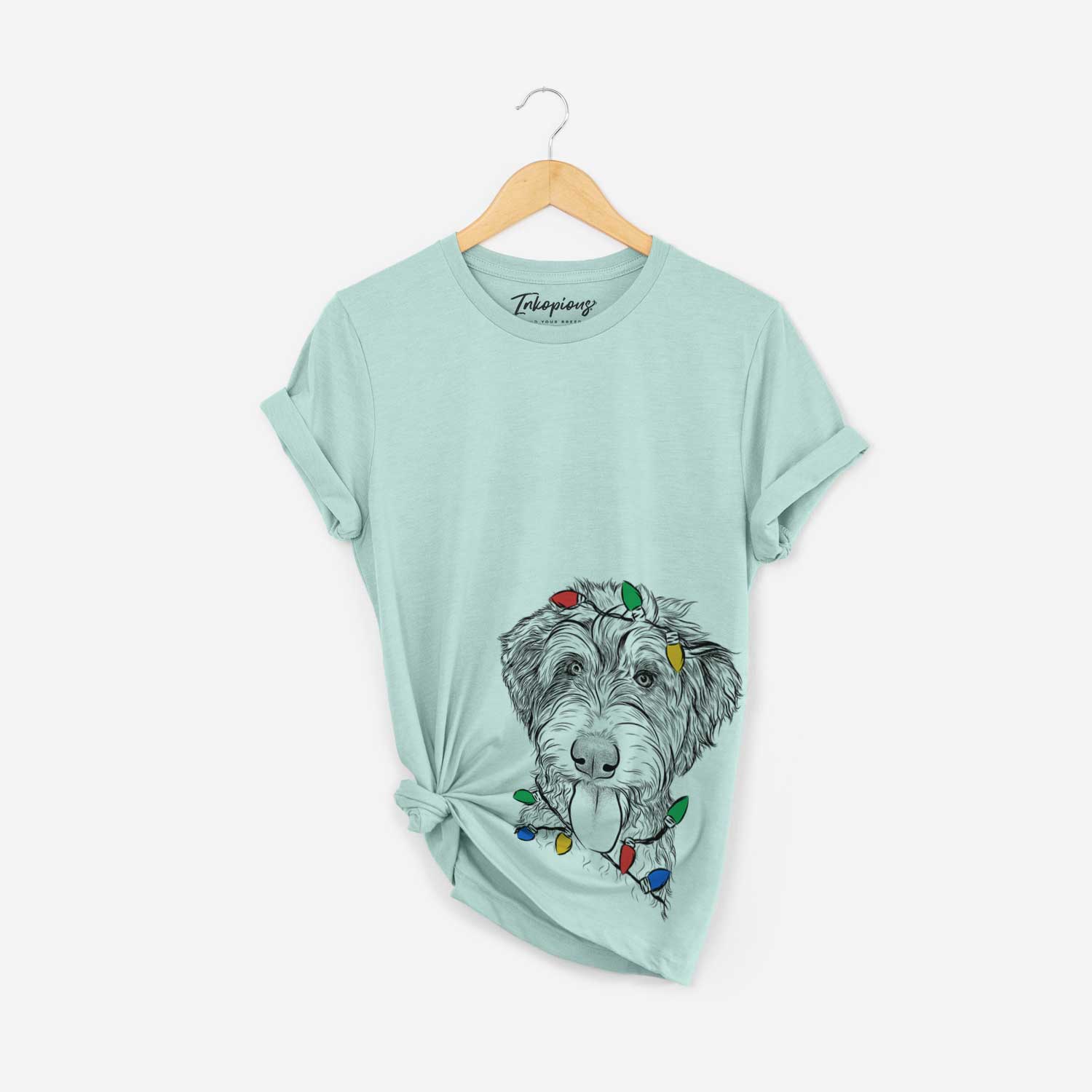 Hand-drawn sketch of Myrtle Mae the Aussiedoodle wrapped in Christmas lights on a Heather Sage Unisex crewneck