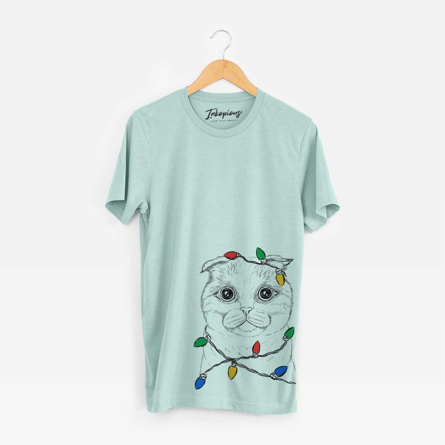 Hand-drawn sketch of Neko the Scottish Fold Cat wrapped in Christmas lights on a Heather Sage Unisex crewneck