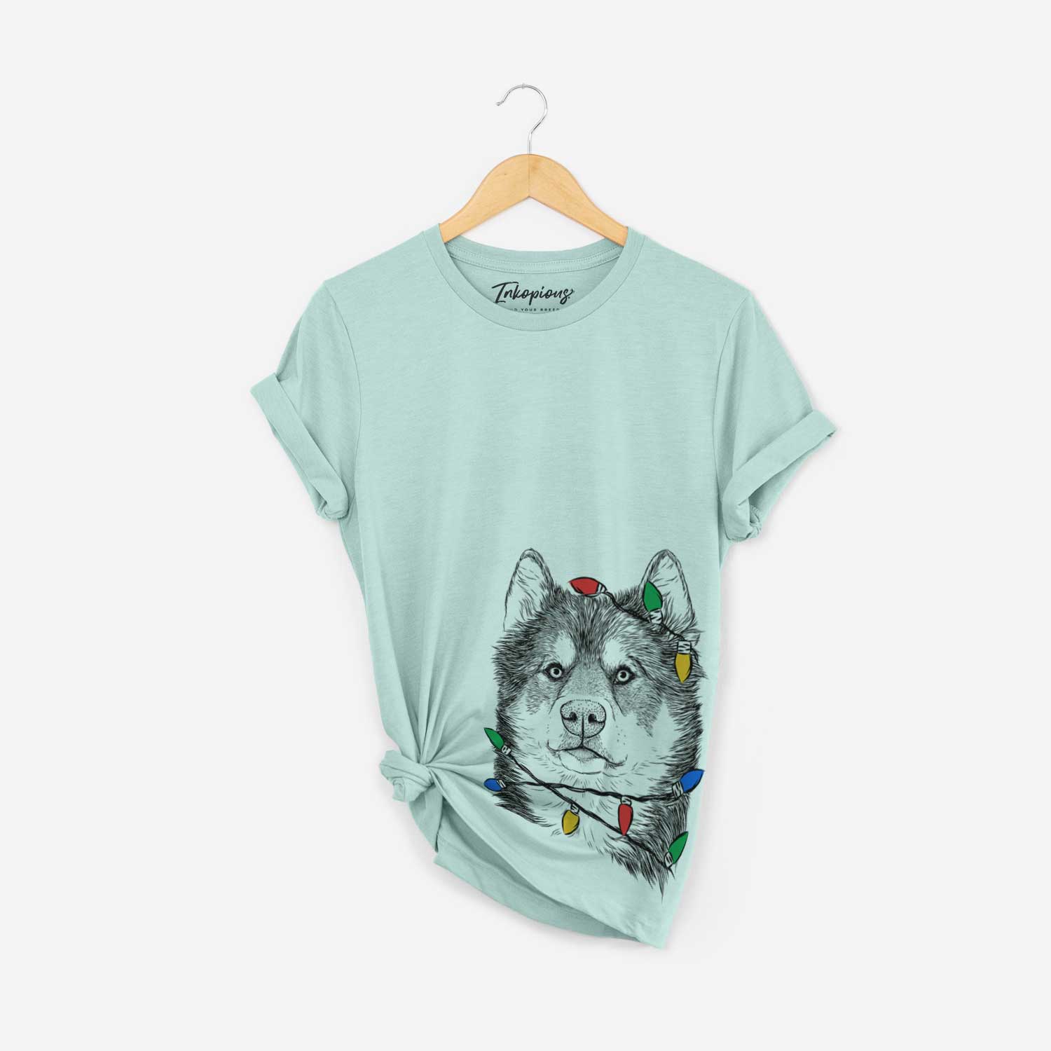 Hand-drawn sketch of Oskar the Canadian Eskimo Dog wrapped in Christmas lights on a Heather Sage Unisex crewneck