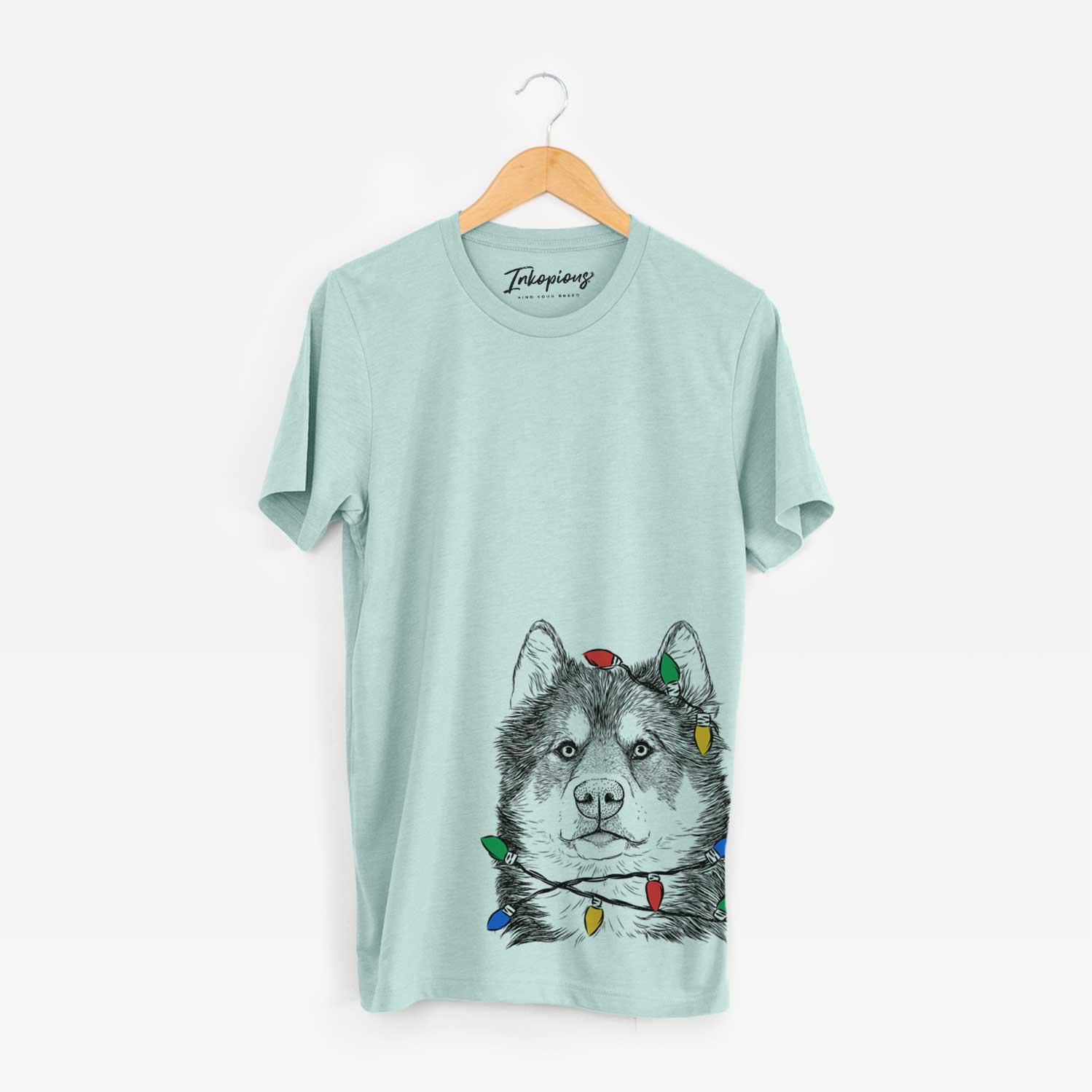 Hand-drawn sketch of Oskar the Canadian Eskimo Dog wrapped in Christmas lights on a Heather Sage Unisex crewneck