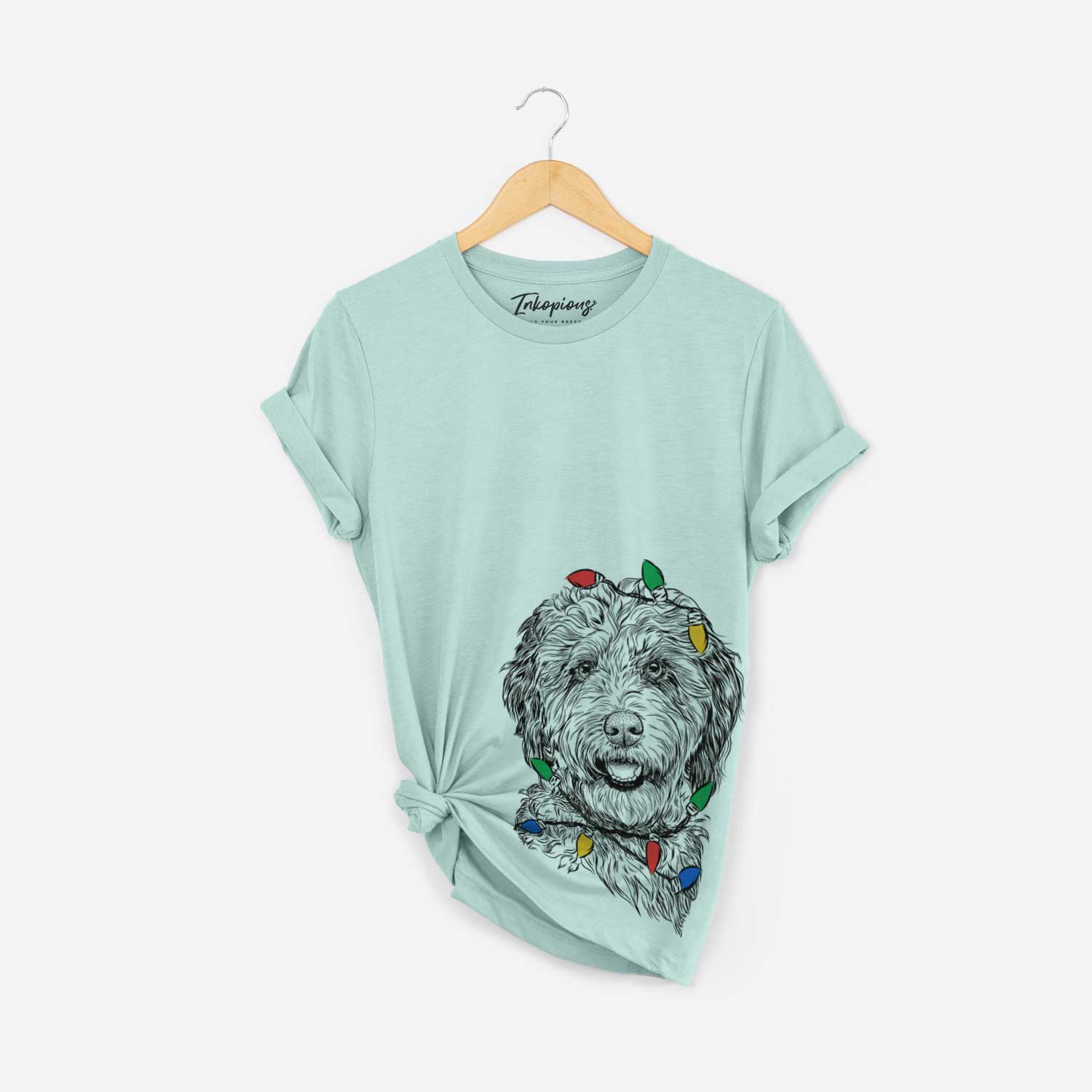 Hand-drawn sketch of Palmer the Aussiedoodle wrapped in Christmas lights on a Heather Sage Unisex crewneck