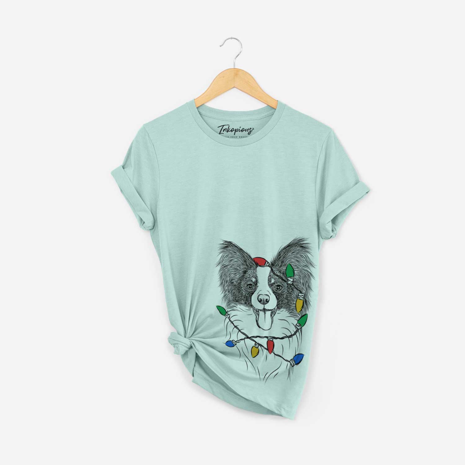 Hand-drawn sketch of Patrick the Papillon wrapped in Christmas lights on a Heather Sage Unisex crewneck