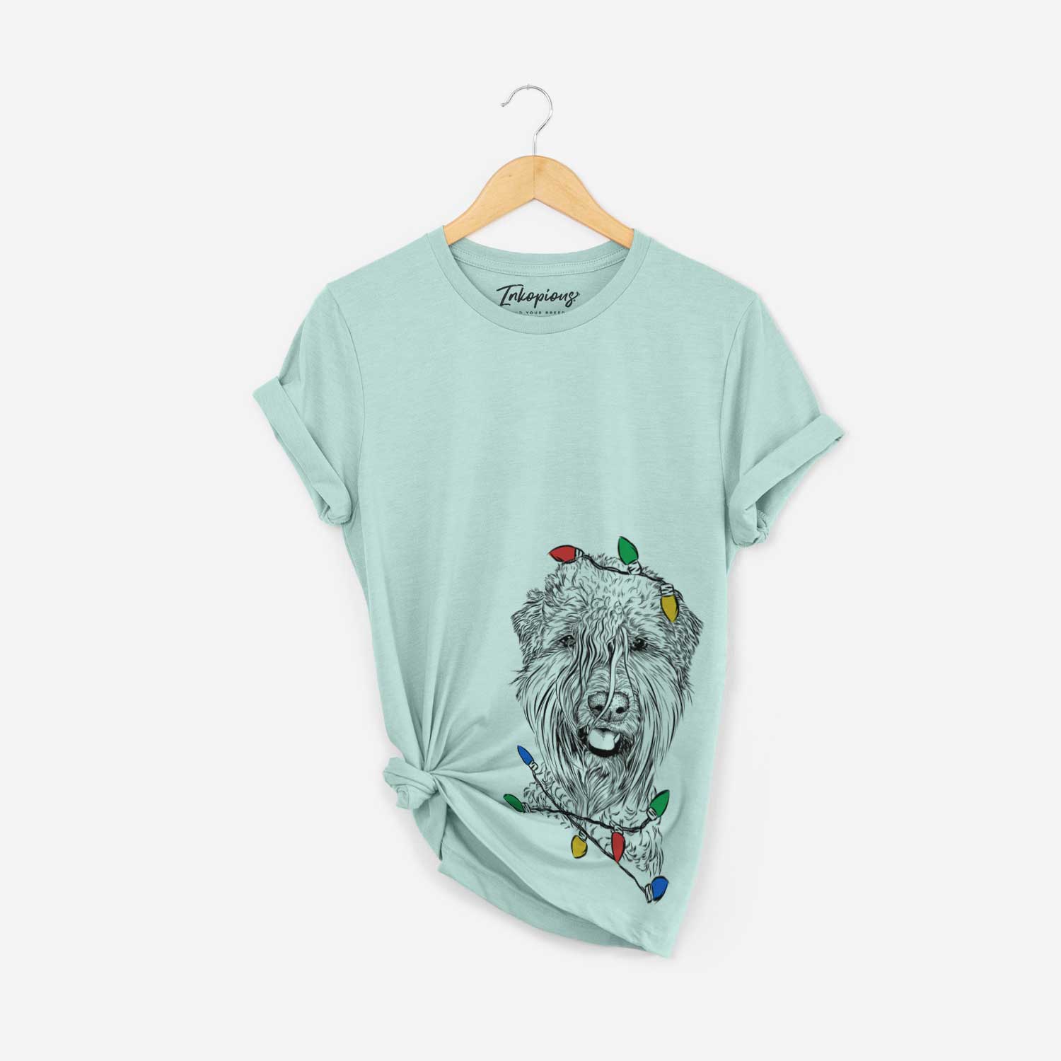 Hand-drawn sketch of Pierre the Soft Coated Wheaten Terrier wrapped in Christmas lights on a Heather Sage Unisex crewneck
