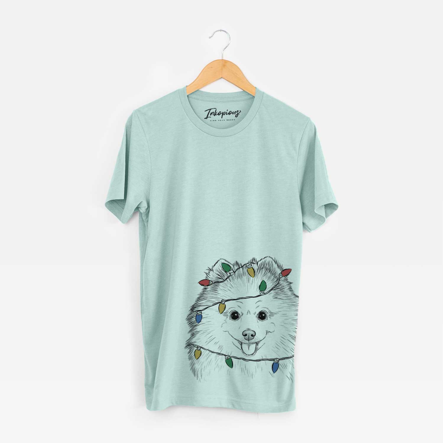 Hand-drawn sketch of Piper Jo the Pomeranian wrapped in Christmas lights on a Heather Sage Unisex crewneck