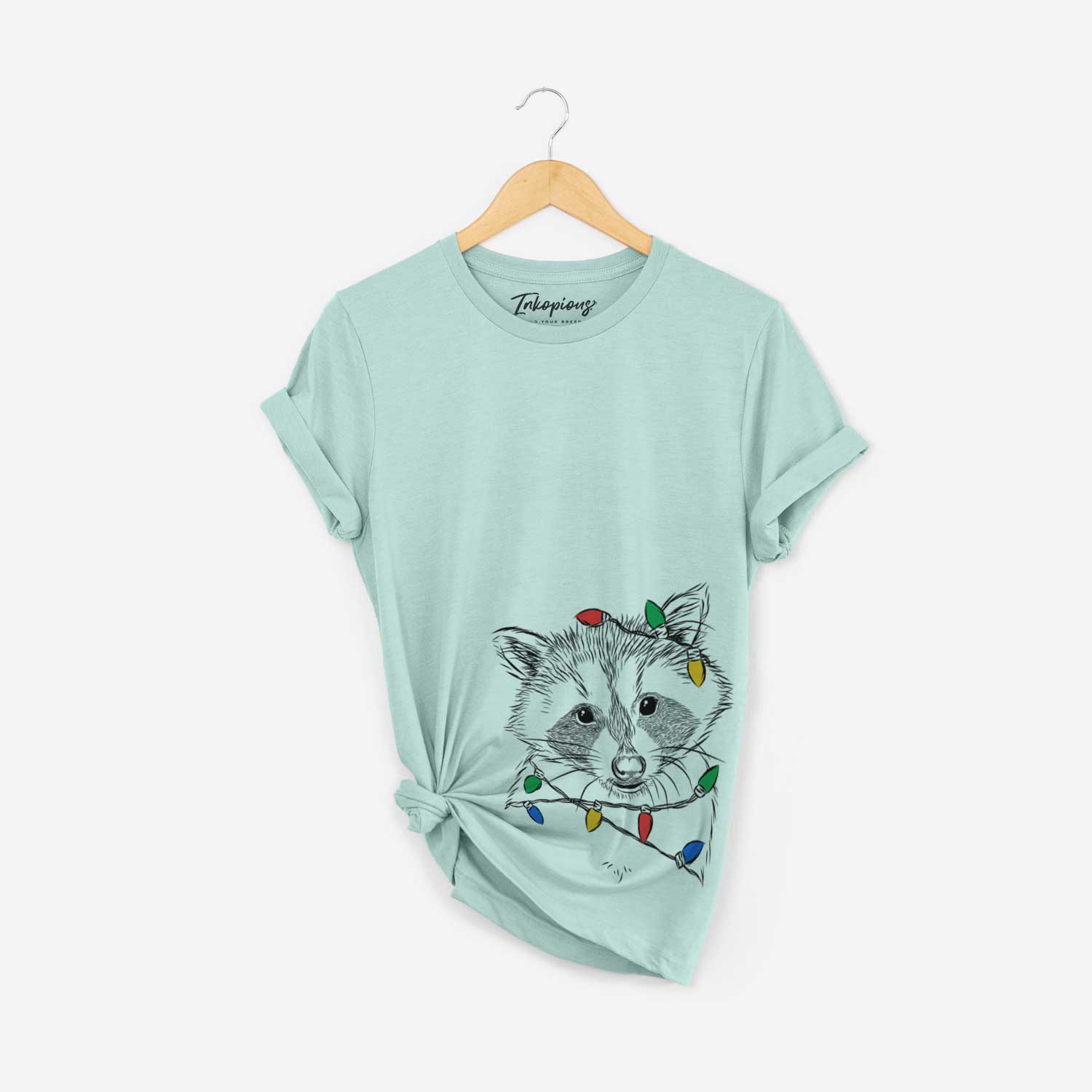 Hand-drawn sketch of Randy the Raccoon wrapped in Christmas lights on a Heather Sage Unisex crewneck