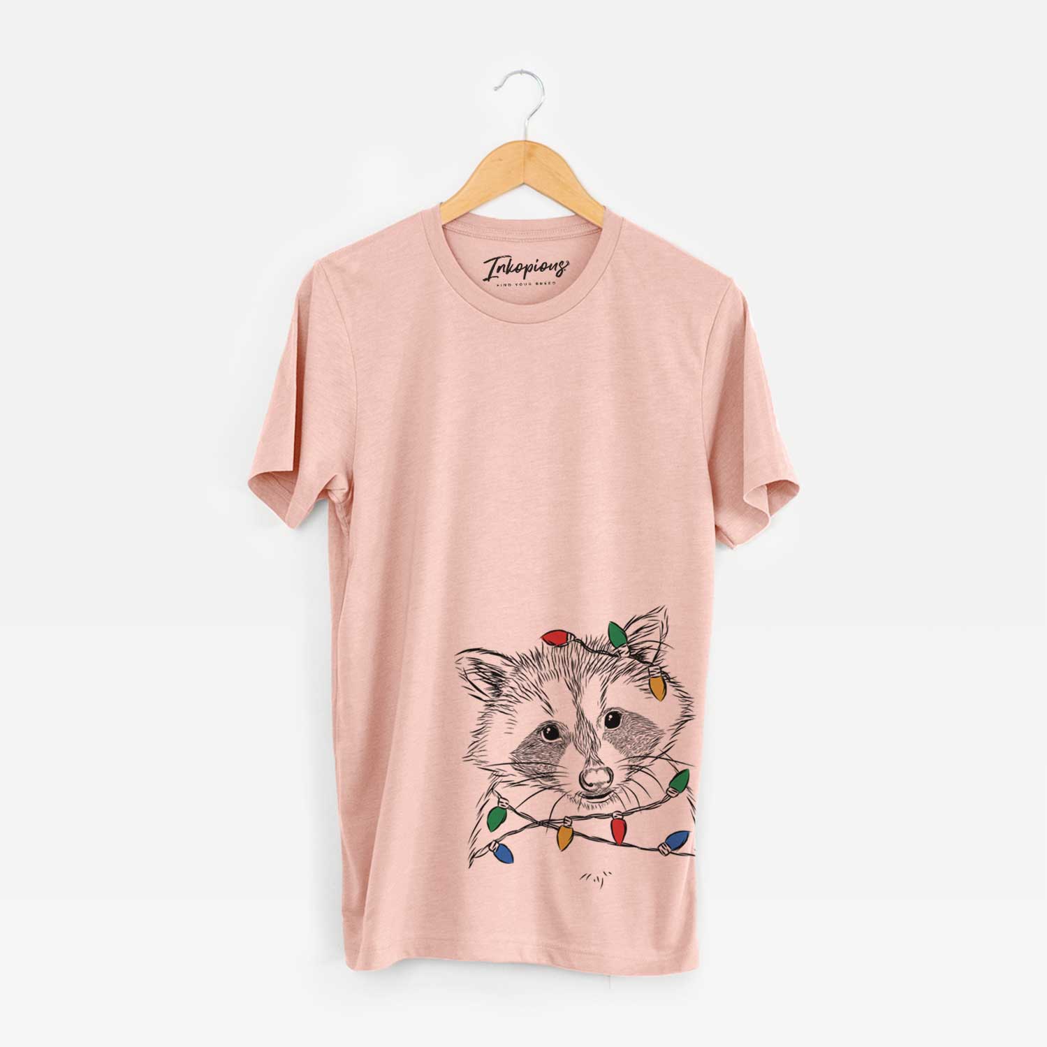 Hand-drawn sketch of Randy the Raccoon wrapped in Christmas lights on a Peach Unisex crewneck