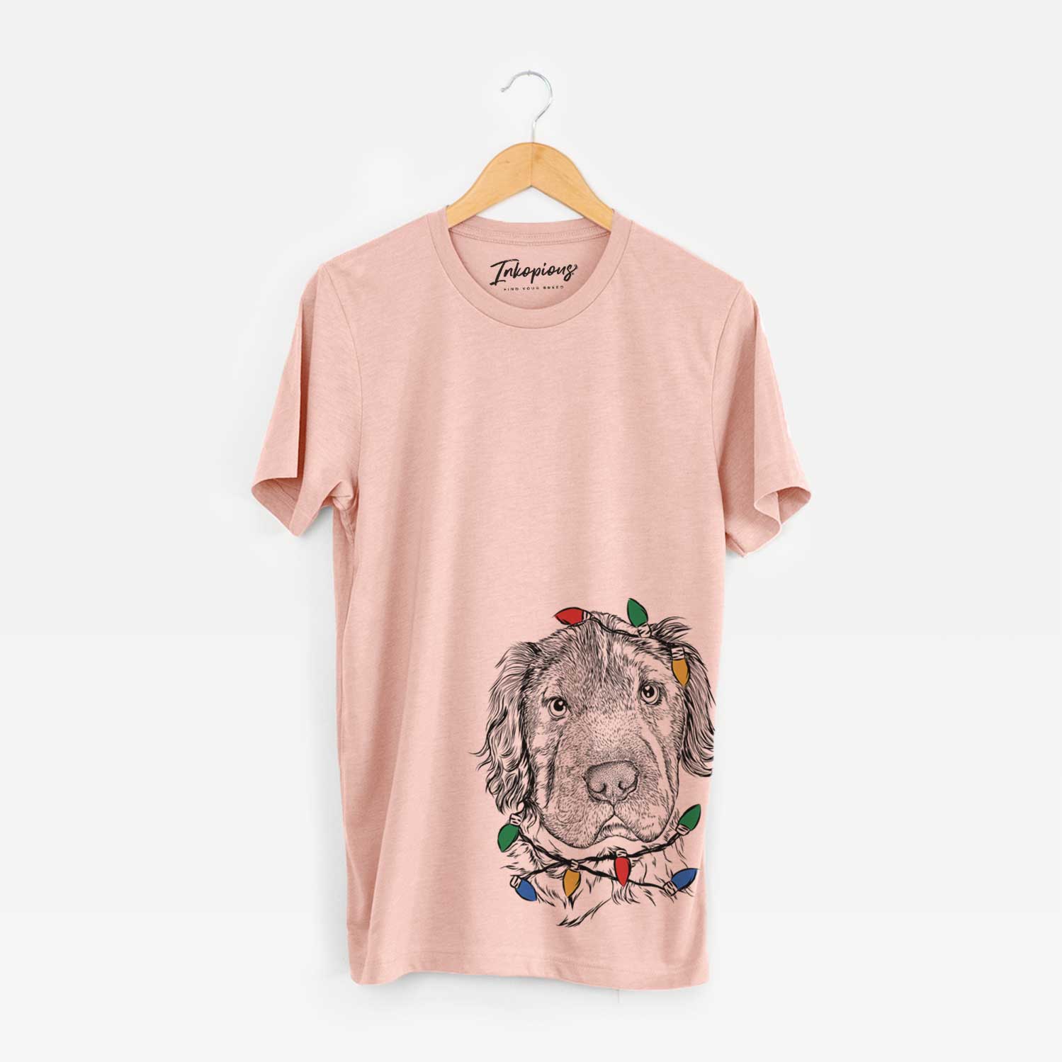 Hand-drawn sketch of Rex the Mini Hippo wrapped in Christmas lights on a Peach Unisex crewneck