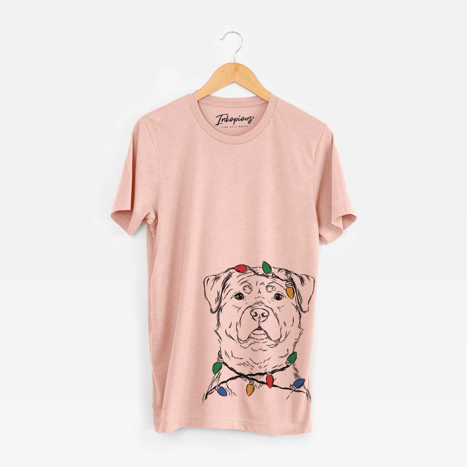 Hand-drawn sketch of Rocky the Rottweiler wrapped in Christmas lights on a Peach Unisex crewneck