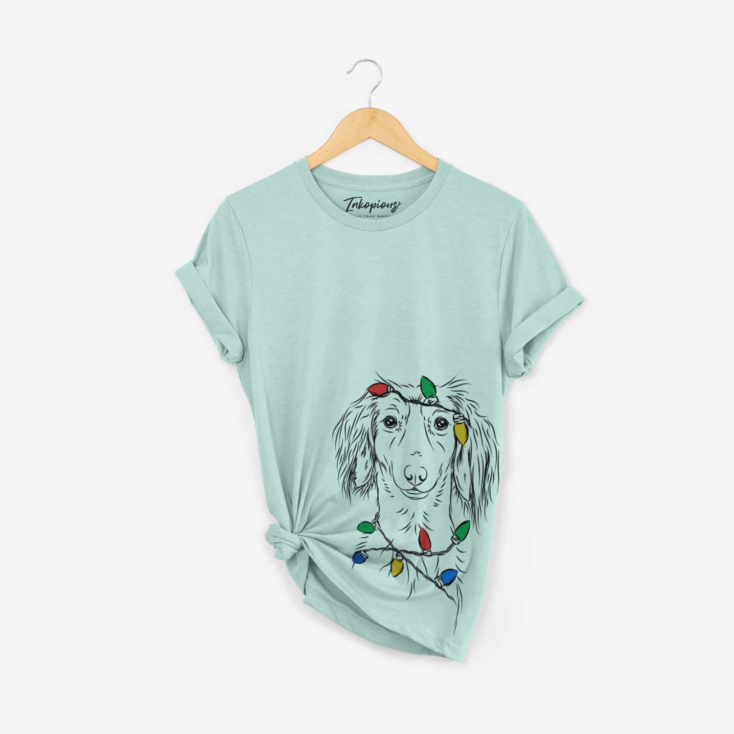 Hand-drawn sketch of Roux the Long Haired Dachshund wrapped in Christmas lights on a Heather Sage Unisex crewneck