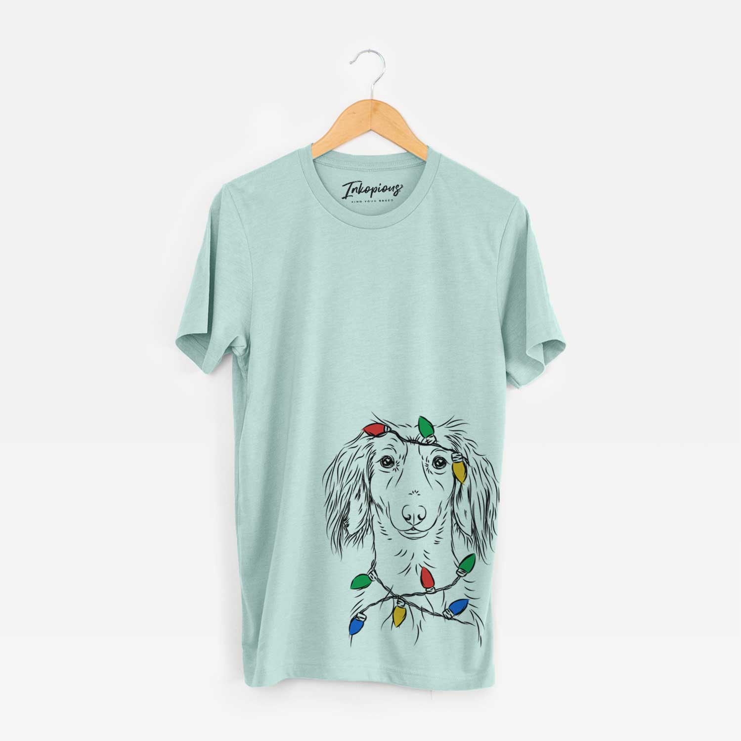 Hand-drawn sketch of Roux the Long Haired Dachshund wrapped in Christmas lights on a Heather Sage Unisex crewneck
