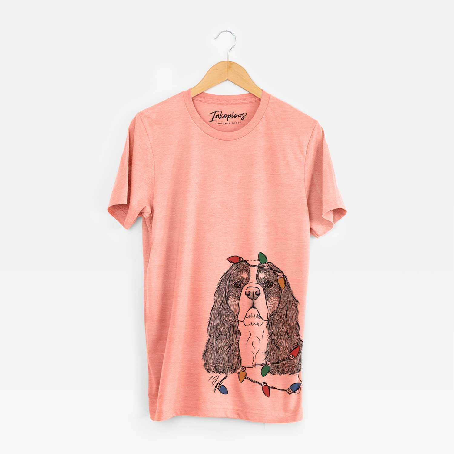 Hand-drawn sketch of Sebastian the Cavalier King Charles Spaniel wrapped in Christmas lights on a Sunset Unisex crewneck