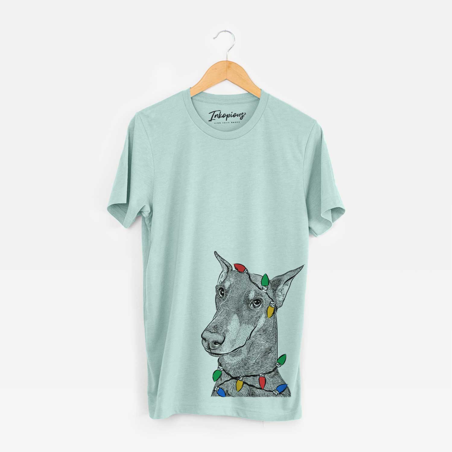 Hand-drawn sketch of Shelby the Doberman Pinscher wrapped in Christmas lights on a Heather Sage Unisex crewneck