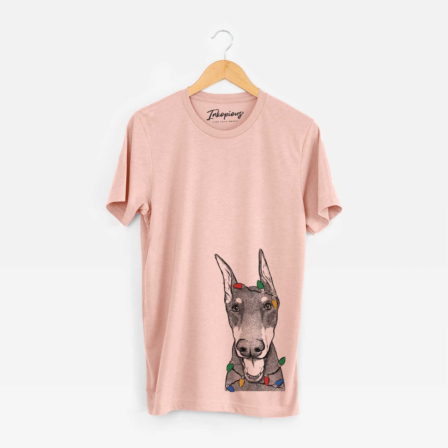 Hand-drawn sketch of Sir Duke the Doberman Pinscher wrapped in Christmas lights on a Peach Unisex crewneck