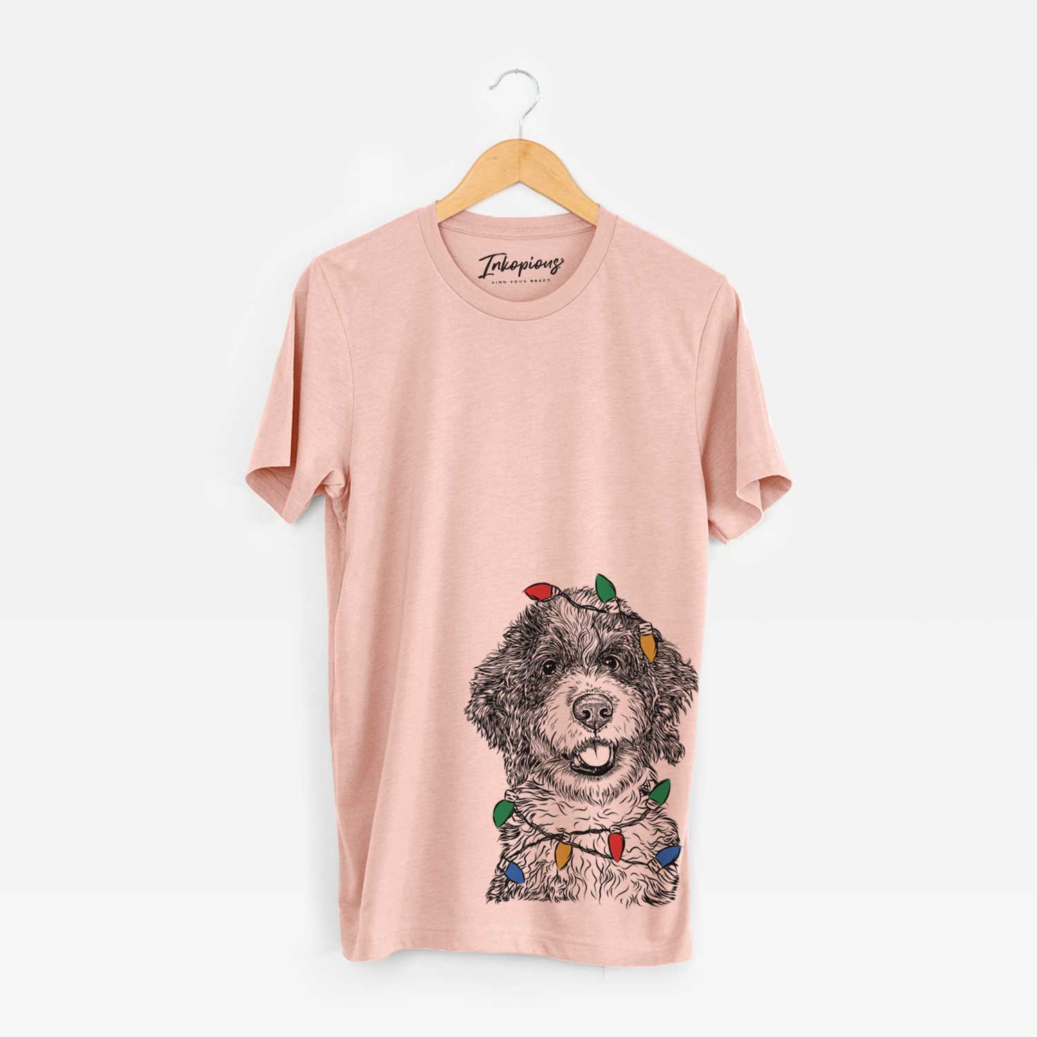 Hand-drawn sketch of Smoky the Bernedoodle Puppy wrapped in Christmas lights on a Peach Unisex crewneck