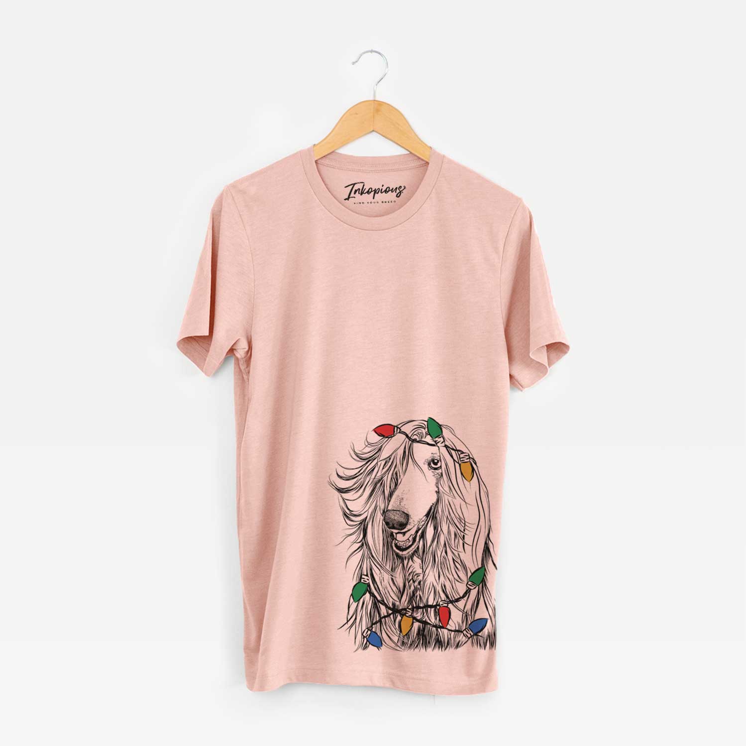 Hand-drawn sketch of Sterling the Afghan Hound wrapped in Christmas lights on a Peach Unisex crewneck