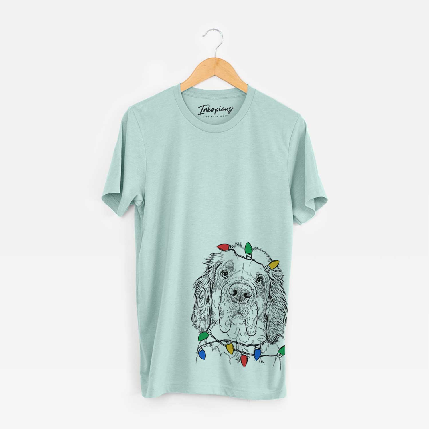 Hand-drawn sketch of Sully the Clumber Spaniel wrapped in Christmas lights on a Heather Sage Unisex crewneck