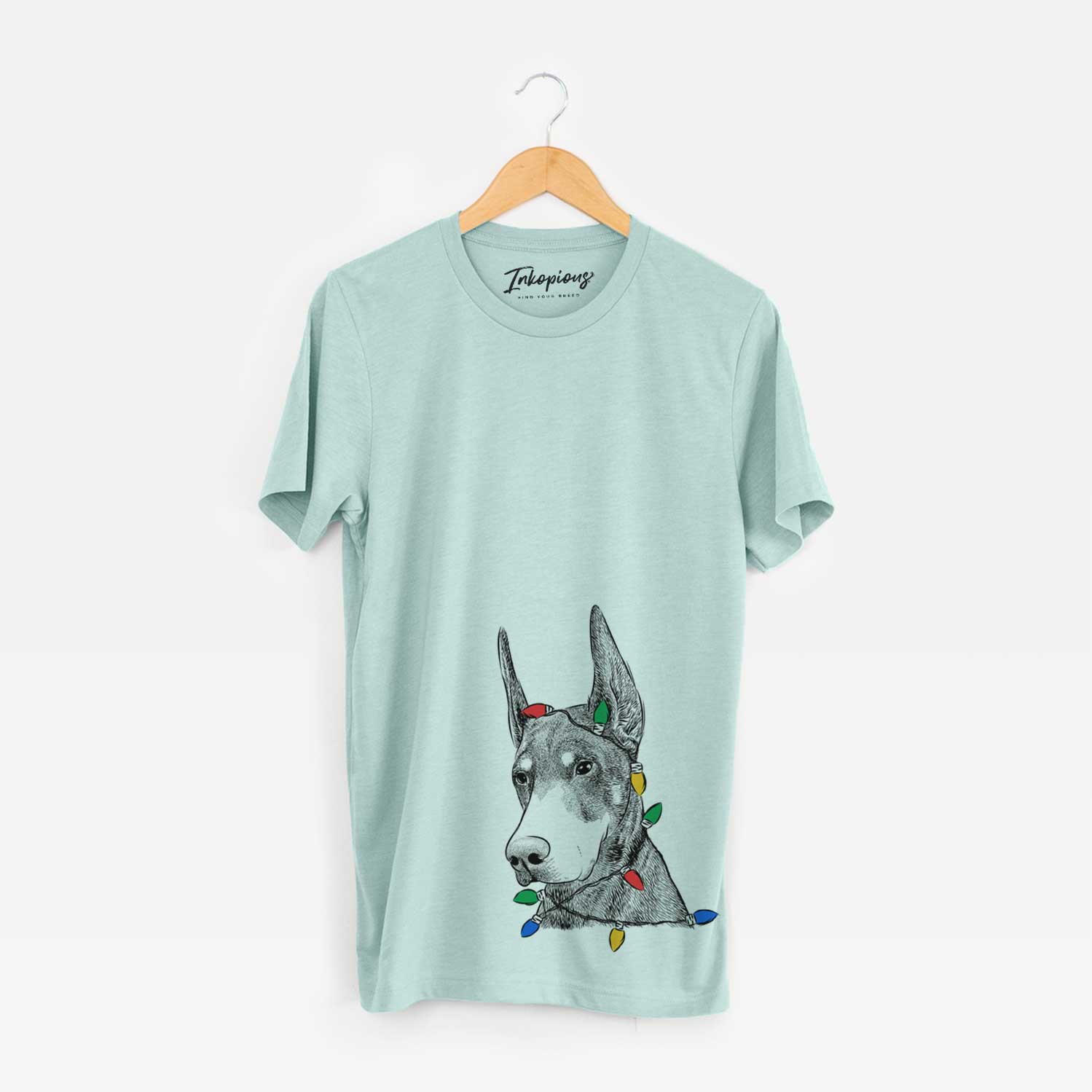 Hand-drawn sketch of Sunny the Doberman Pinscher wrapped in Christmas lights on a Heather Sage Unisex crewneck