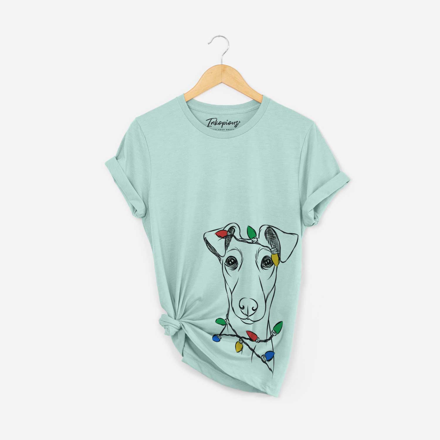 Hand-drawn sketch of Tanner the Fox Terrier wrapped in Christmas lights on a Heather Sage Unisex crewneck