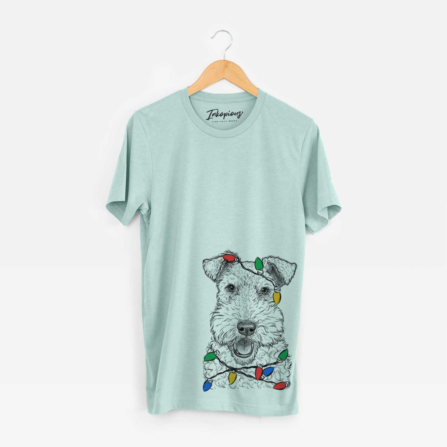 Hand-drawn sketch of Ted the Wire Fox Terrier wrapped in Christmas lights on a Heather Sage Unisex crewneck