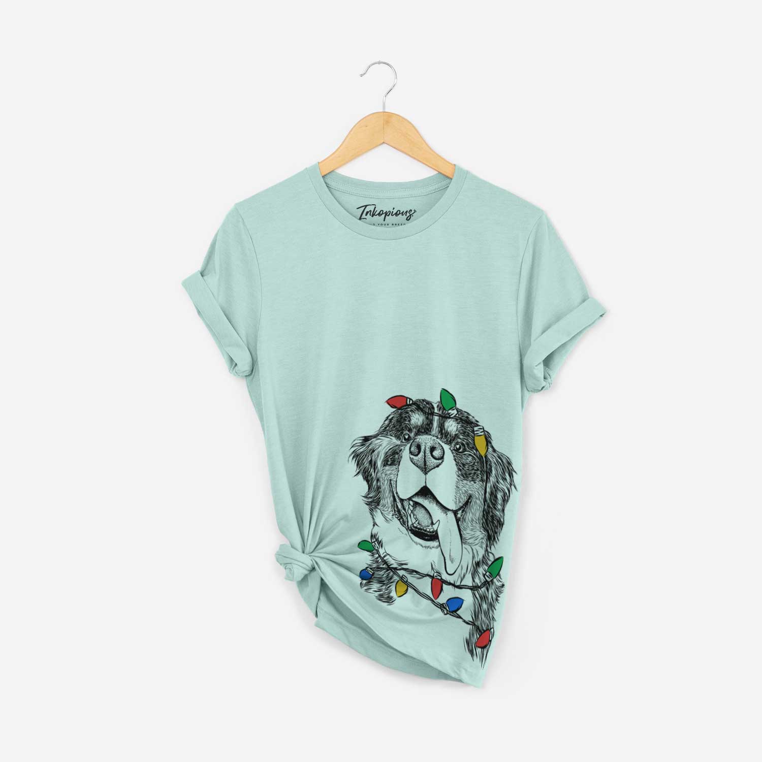 Hand-drawn sketch of Theo the Bernese Mountain Dog wrapped in Christmas lights on a Heather Sage Unisex crewneck
