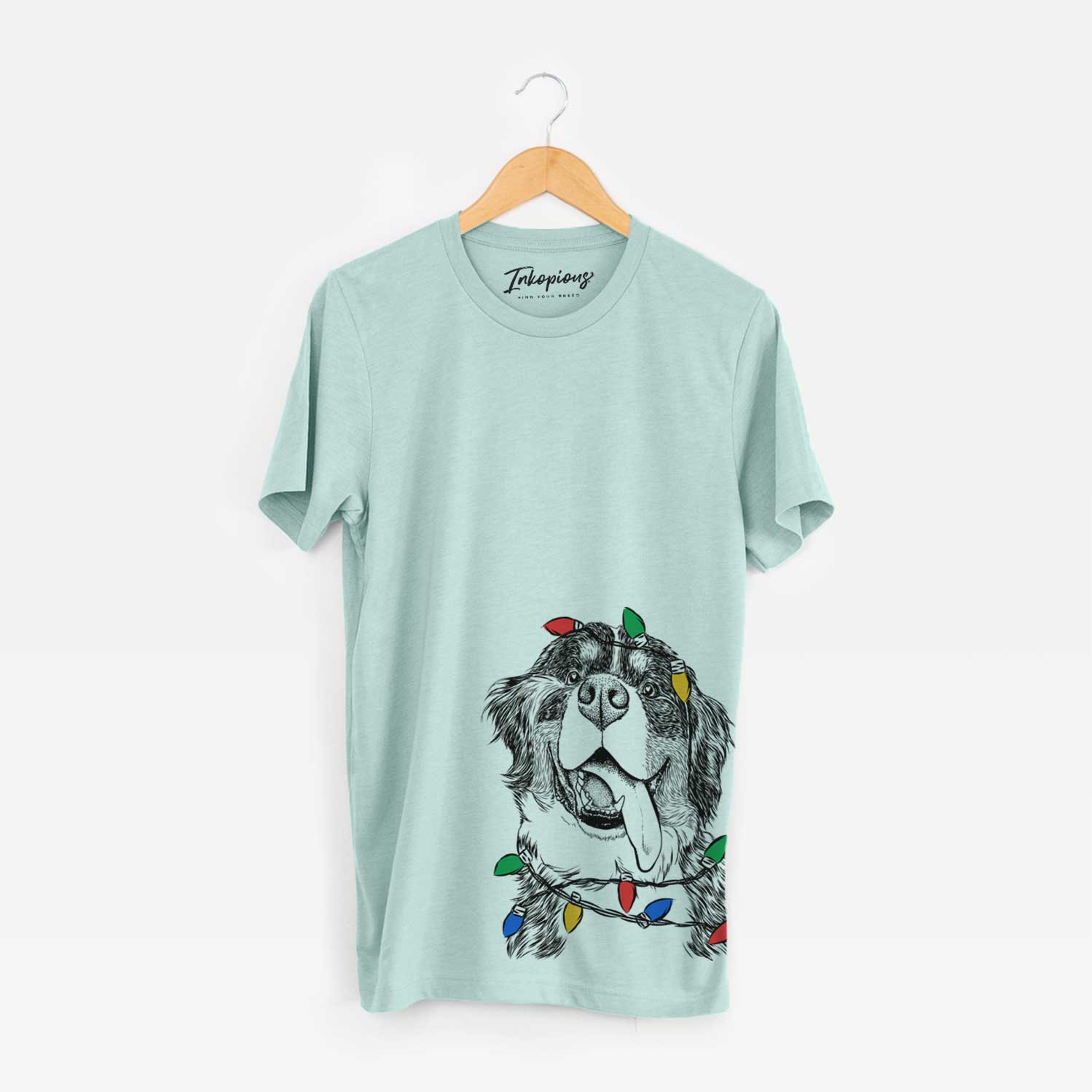 Hand-drawn sketch of Theo the Bernese Mountain Dog wrapped in Christmas lights on a Heather Sage Unisex crewneck