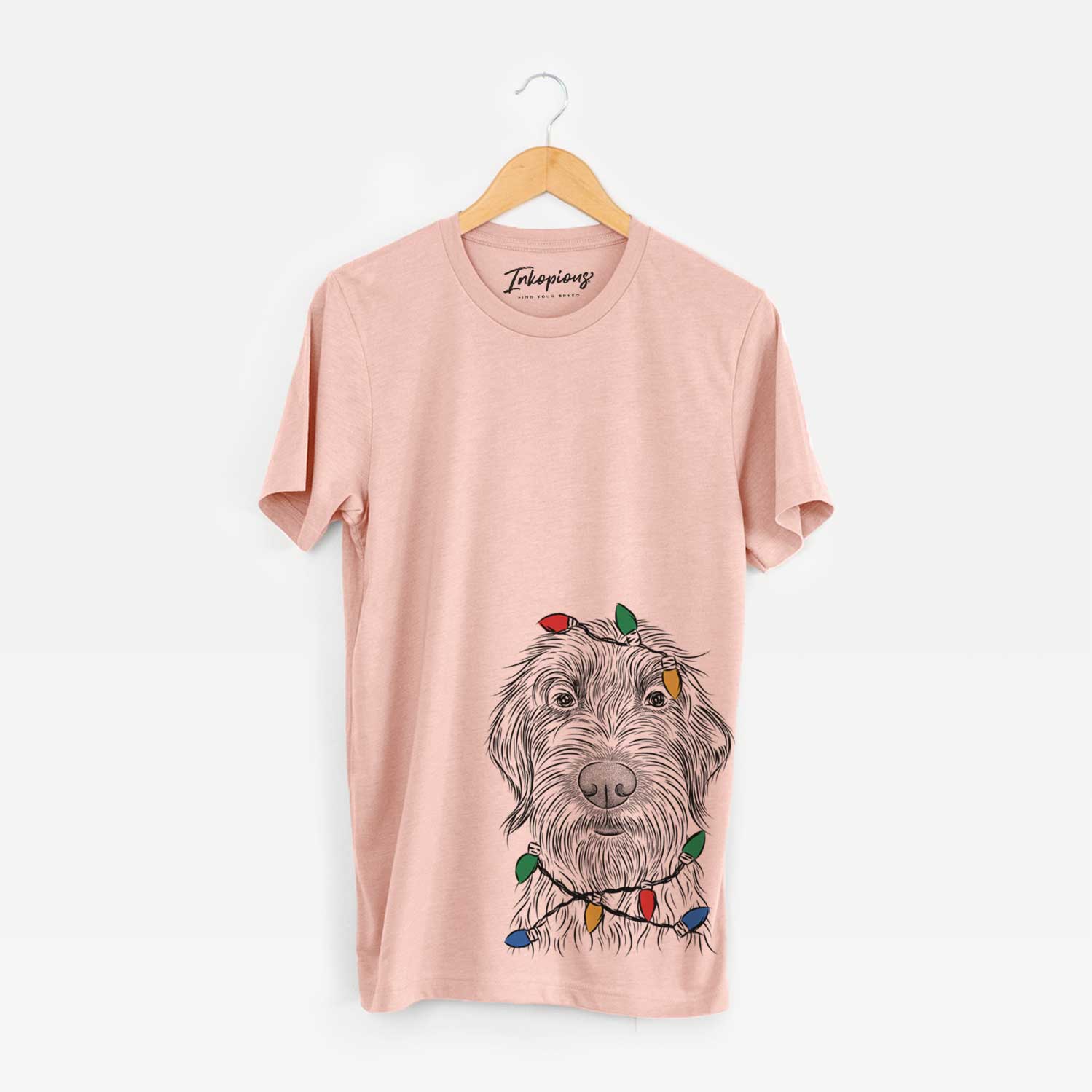 Hand-drawn sketch of Wilkins the Wirehaired Pointing Griffon wrapped in Christmas lights on a Peach Unisex crewneck