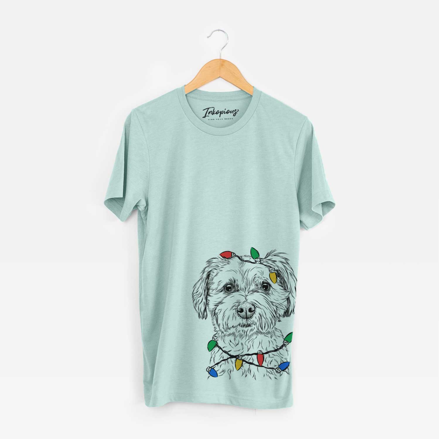 Hand-drawn sketch of Wyatt the Coton de Tulear wrapped in Christmas lights on a Heather Sage Unisex crewneck