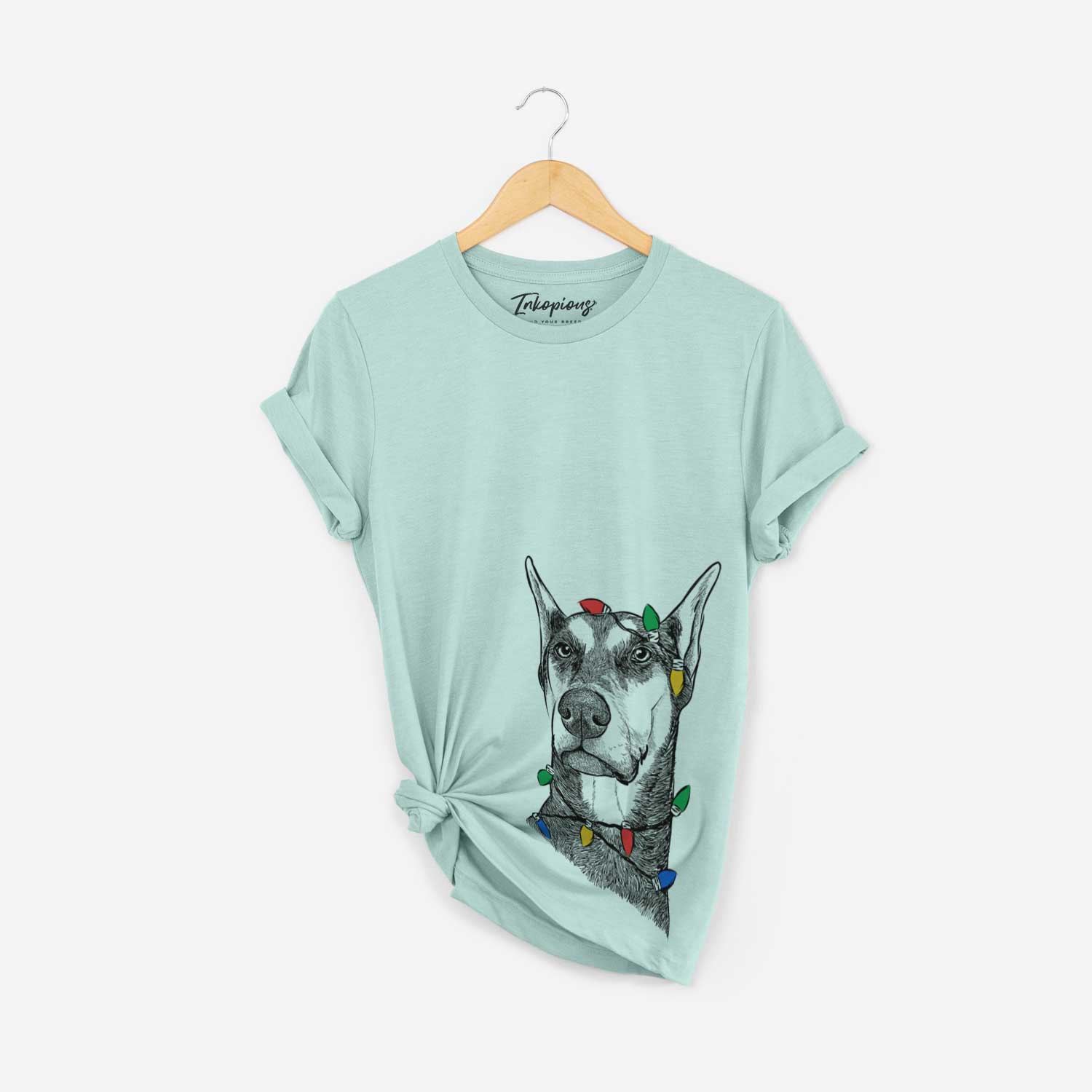 Hand-drawn sketch of Zeus the Doberman Pinscher wrapped in Christmas lights on a Heather Sage Unisex crewneck